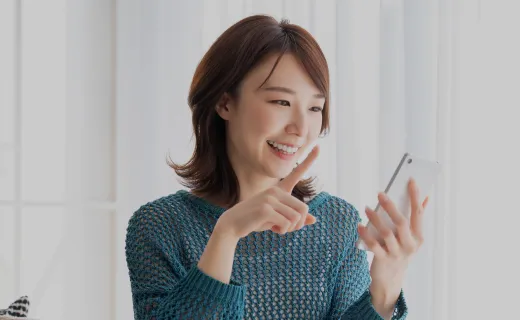 明るい笑顔でスマートフォンを操作している若い女性